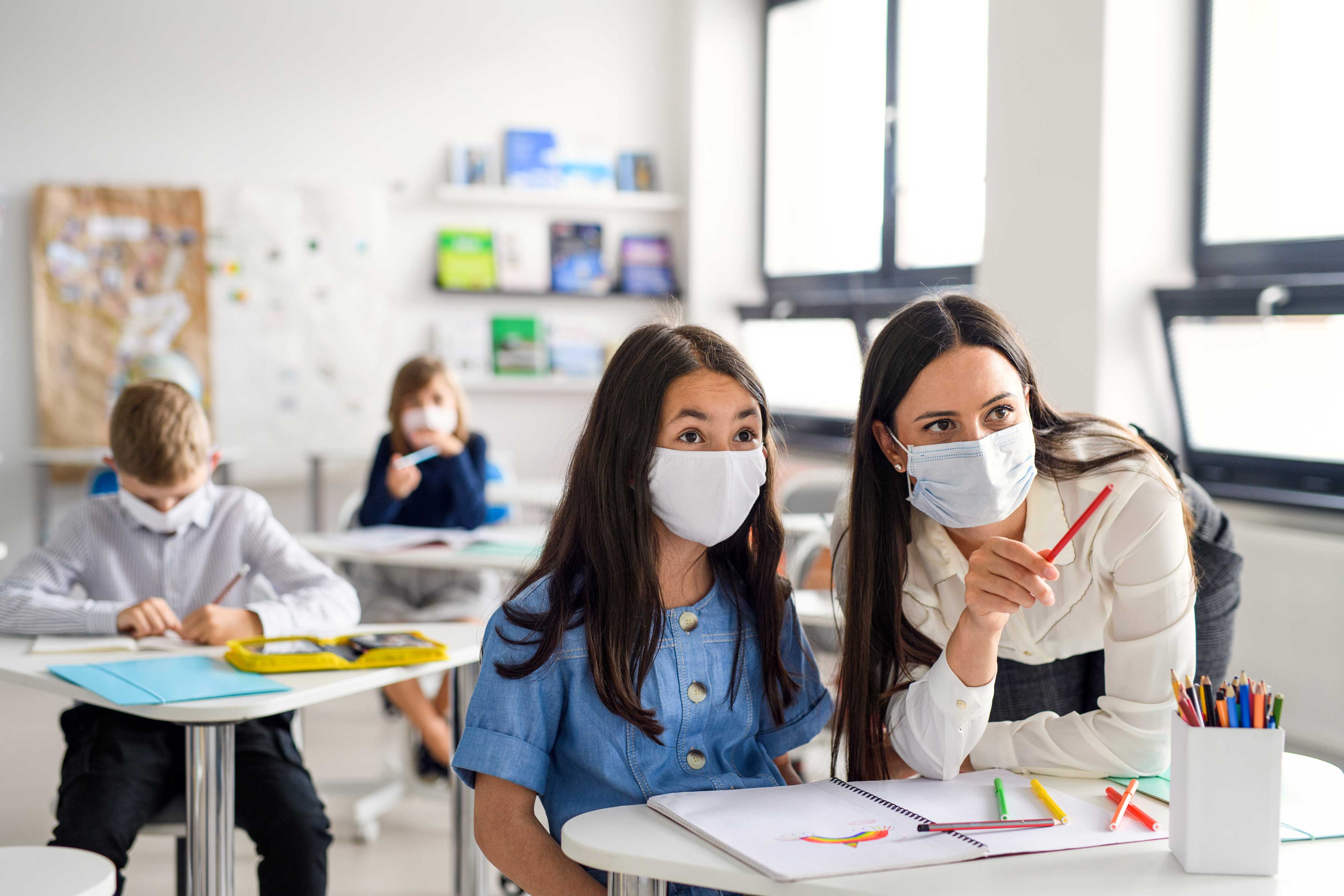 Intéraction entre une enseignante et une élève avec des masques